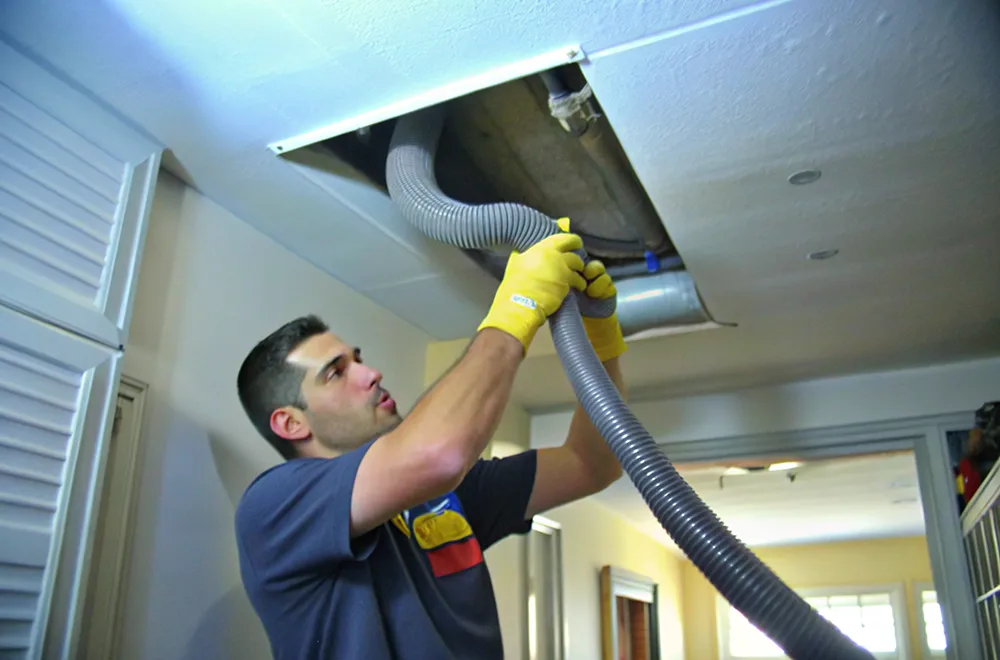a HVAC cleaner putting a pipe into a unit to clean it