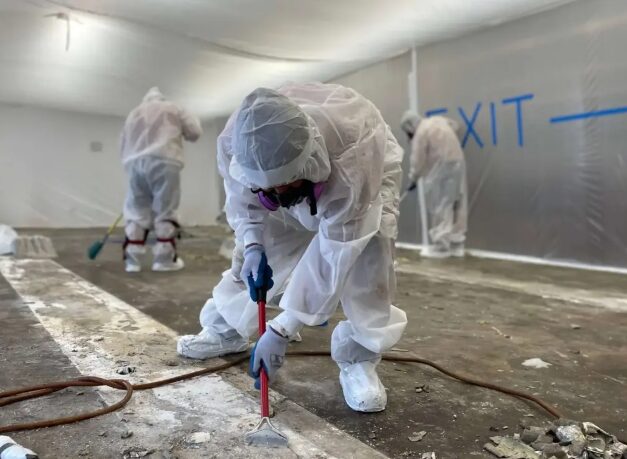 Crew in PPE removing asbestos-containing material