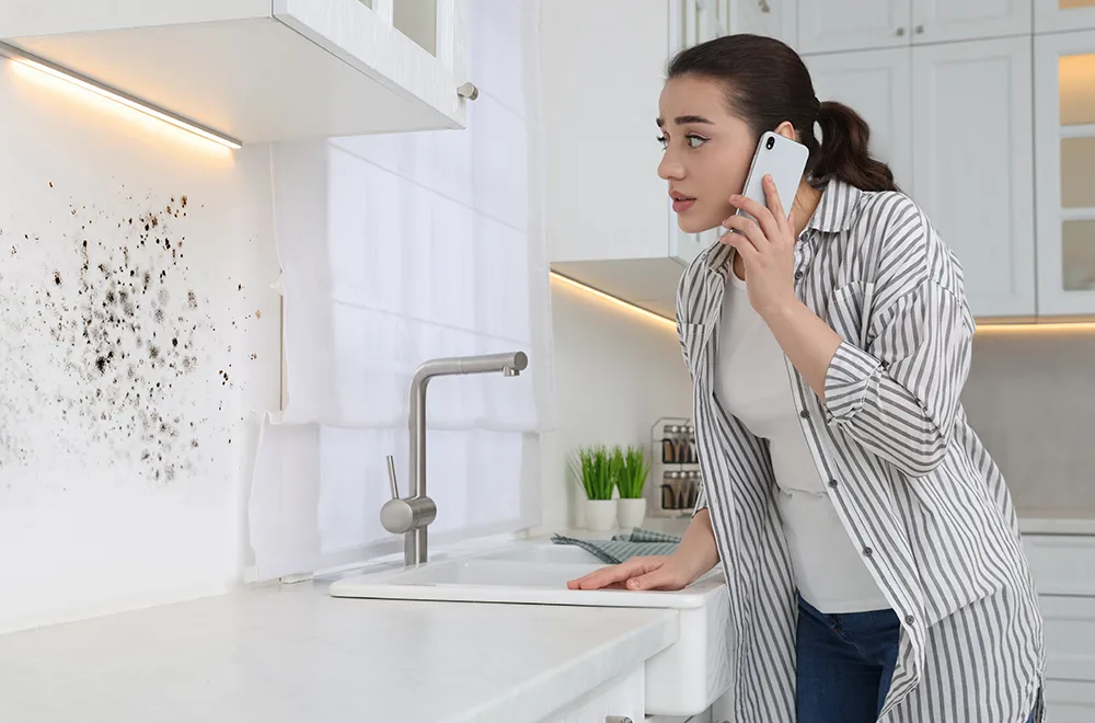 woman looking at mold on her kitchen wall